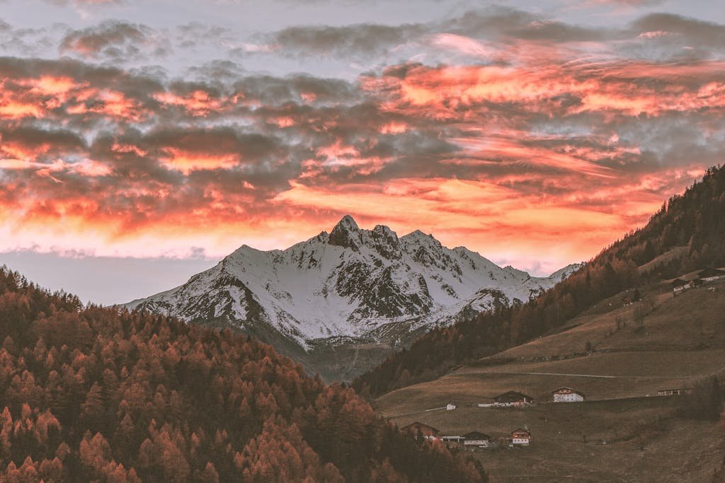 Stunning sunset over snow-capped mountains with vibrant skies and scenic valleys below.