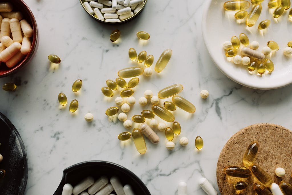 A top view of assorted capsules and pills displayed on a marble surface, showcasing a variety of medicines.